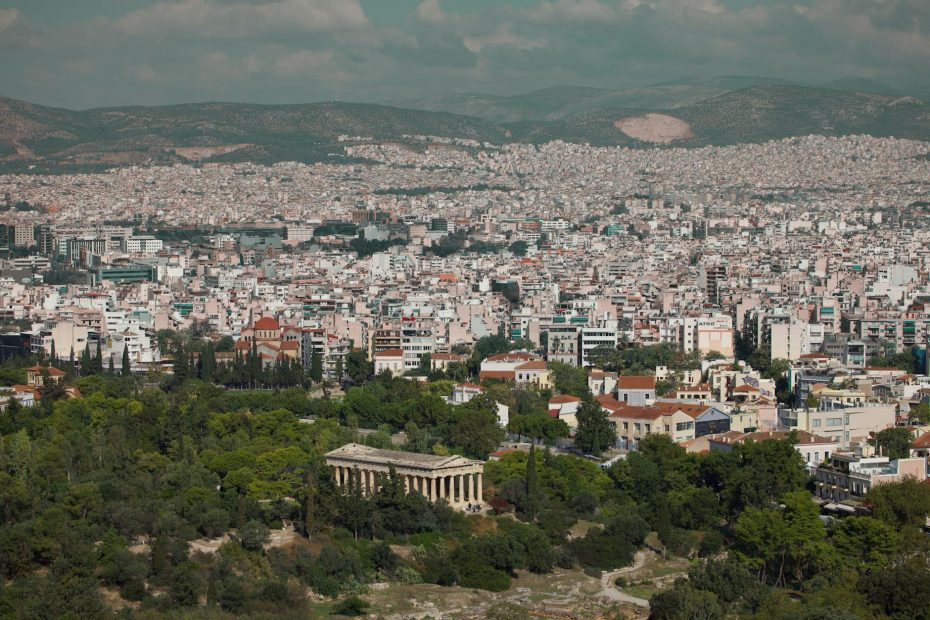 Panoramic view of Athens cityscape with ancient temple and greenery.