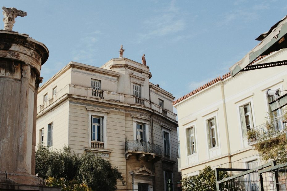 Historic neoclassical building exterior against a bright blue sky, showcasing classic architectural details.
