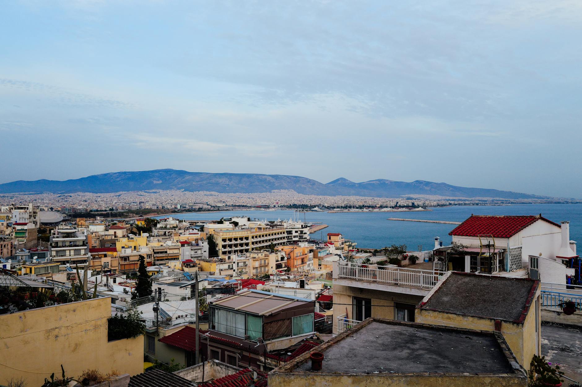Overlooking Athens skyline with mountains and sea, showcasing vibrant urban architecture and coastal beauty.
