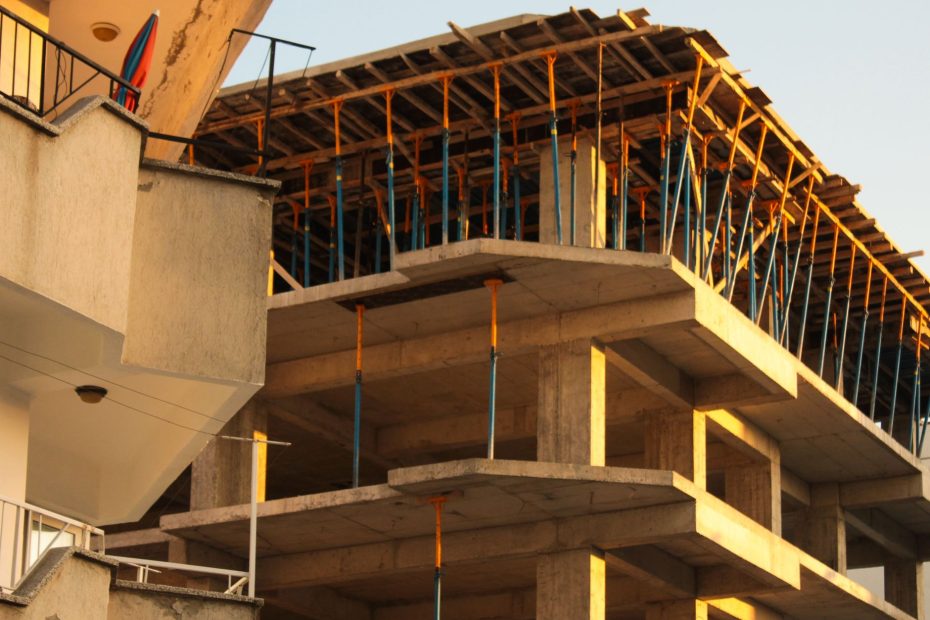 Concrete building under construction with scaffolding lit by warm sunset light.