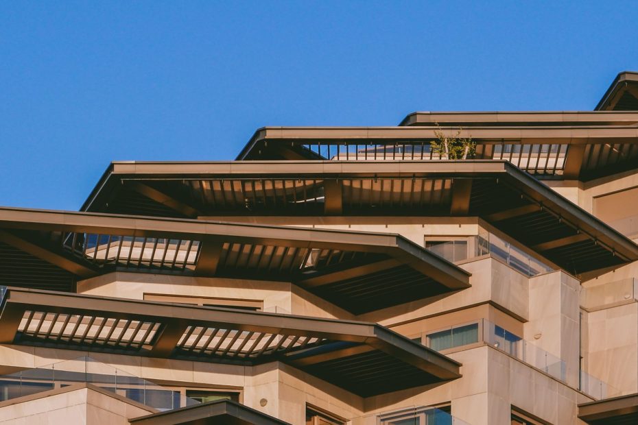 A stunning capture of a modern architectural building with sunlit balconies against a clear blue sky.