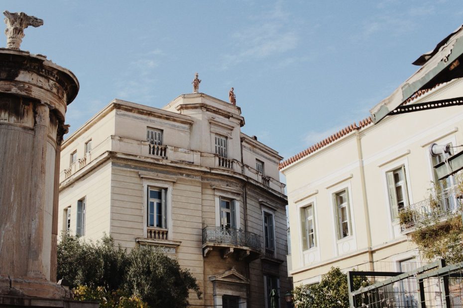 Historic neoclassical building exterior against a bright blue sky, showcasing classic architectural details.